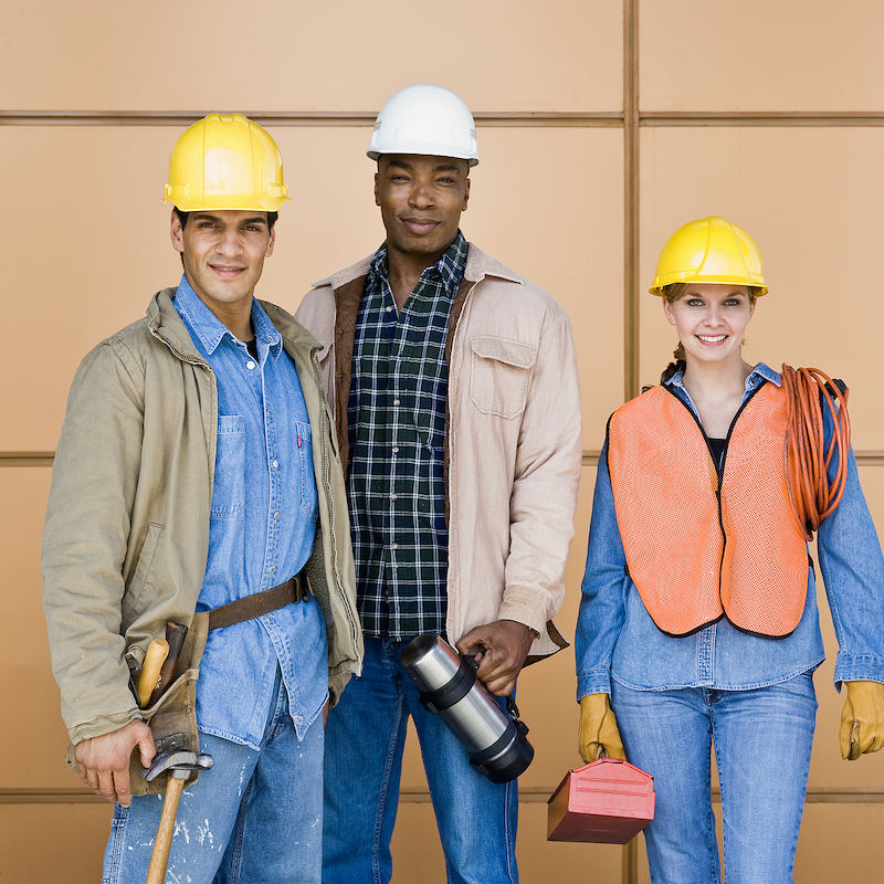 Multi-ethnic construction workers posing in hard-hats with tools